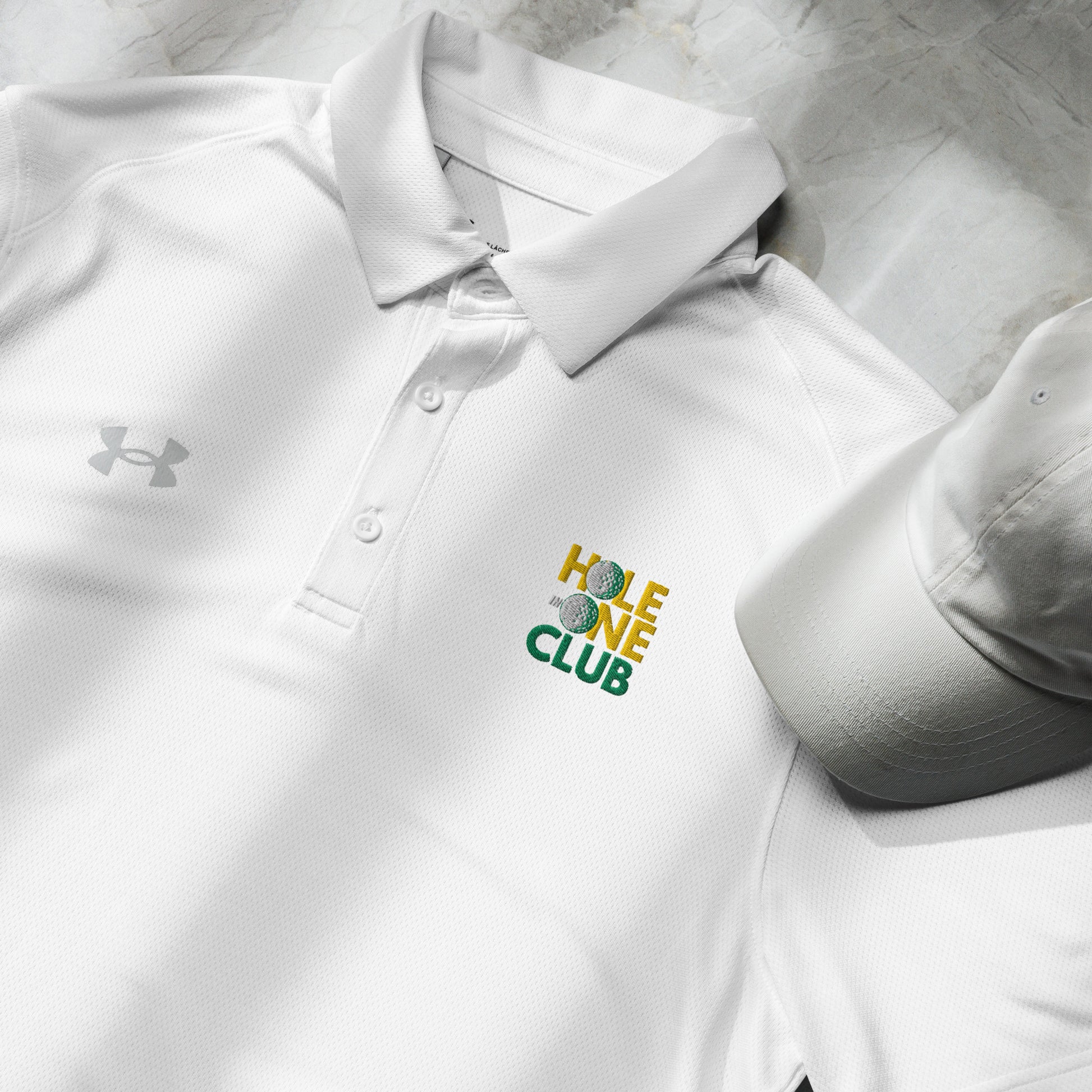 white polo shirt with hole in one club text and golf ball motif